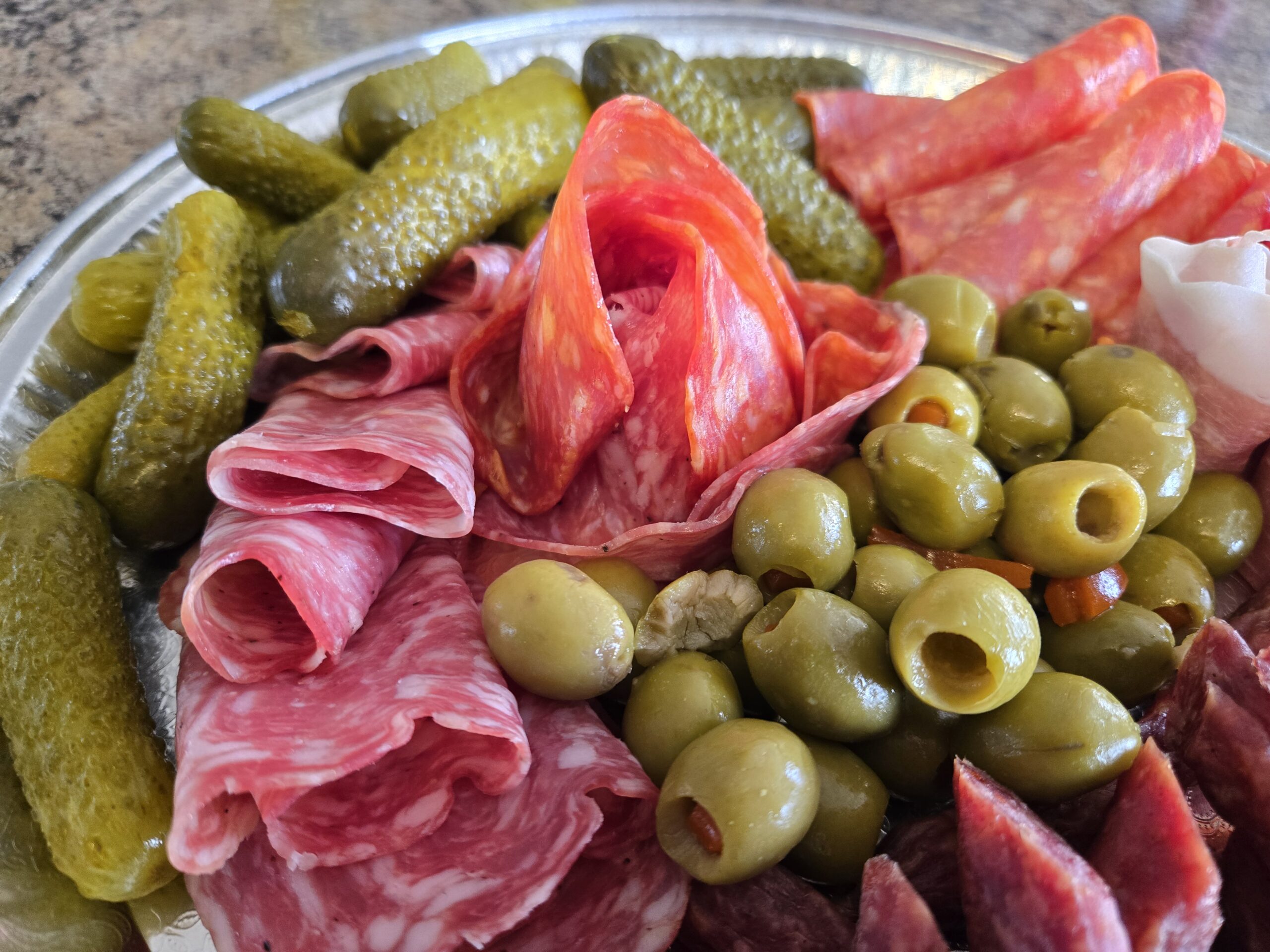 A platter featuring various cured meats, olives, and pickles arranged artfully.