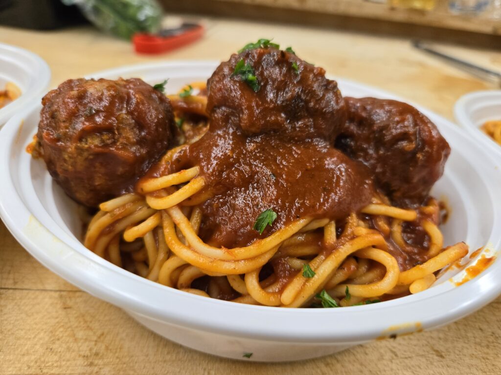 A bowl of spaghetti topped with meatballs and marinara sauce, garnished with parsley.